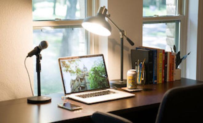 laptop at empty desk with microphone and lamp